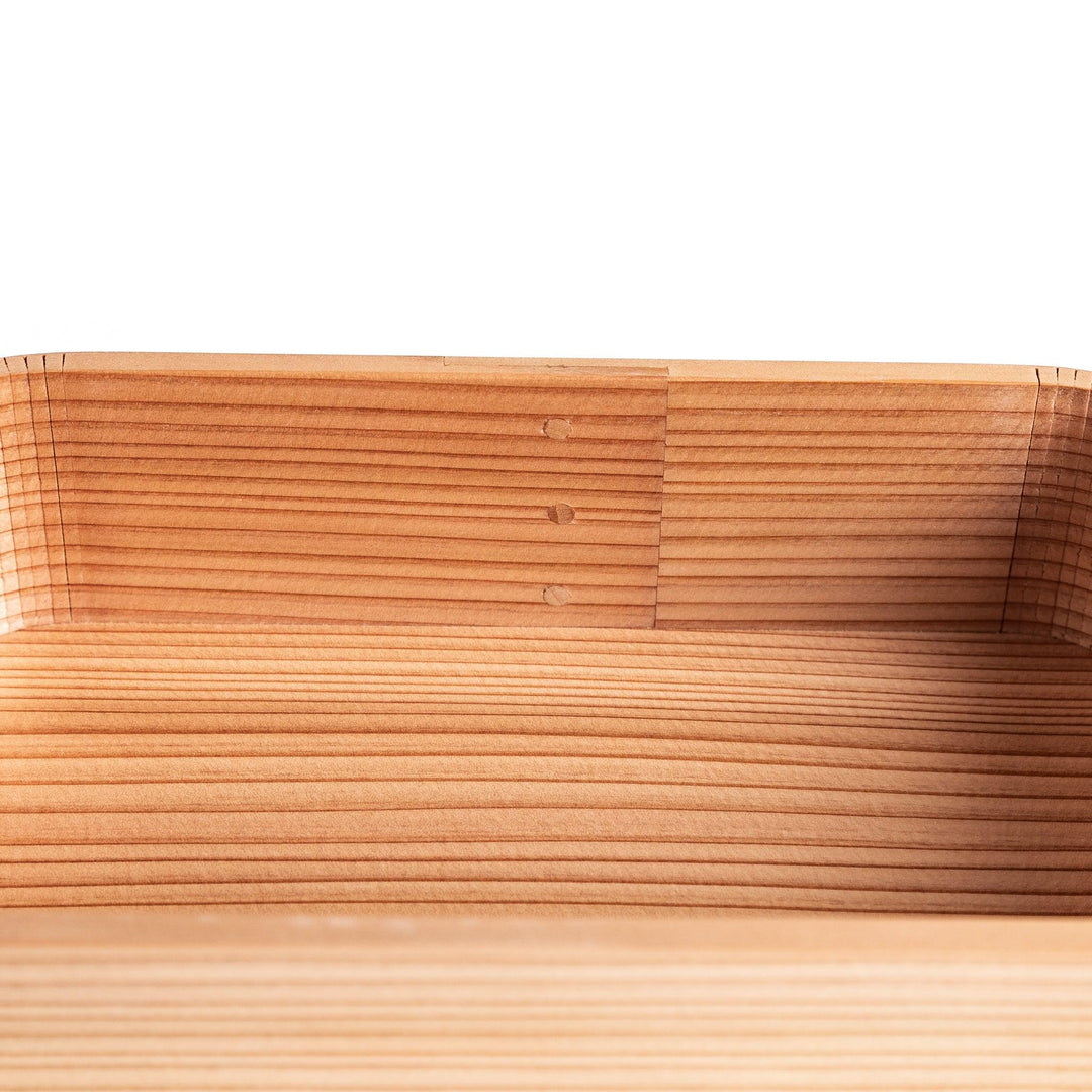 Side view of the Artisan Cedar Bento Box, showcasing its sleek, striped texture and smooth, rounded edges with visible joinery details.