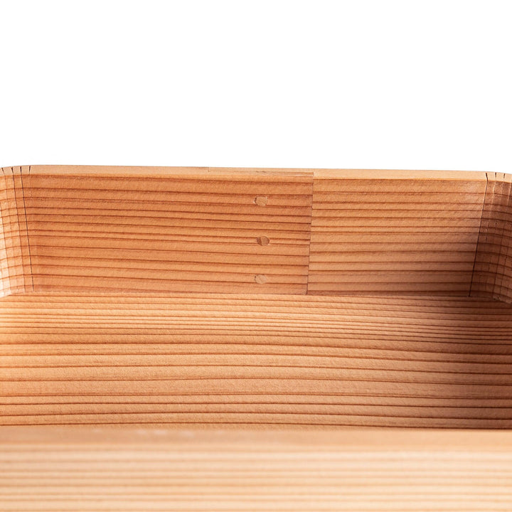 Side view of the Artisan Cedar Bento Box, showcasing its sleek, striped texture and smooth, rounded edges with visible joinery details.