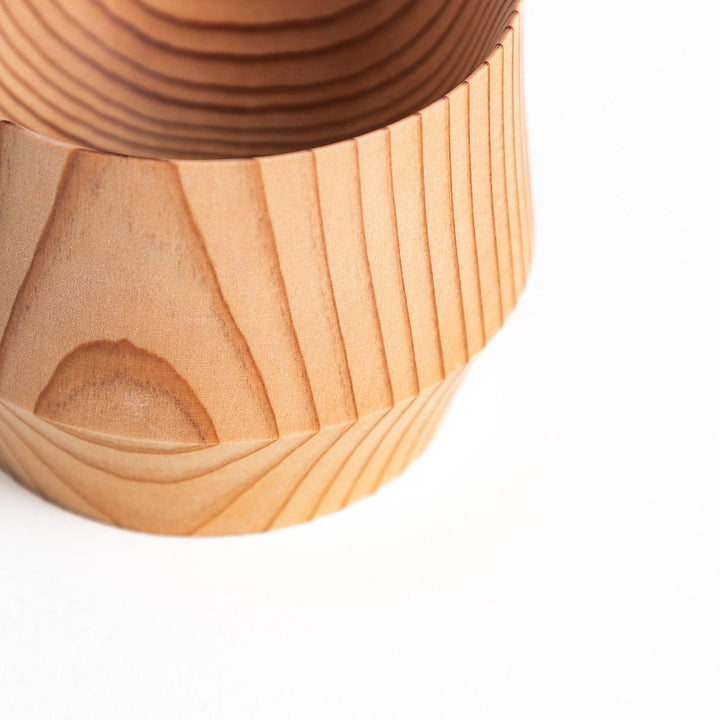 The bottom of a cedar sake cup engraved with the ASAKURA brand, surrounded by natural wood grain that complements the fine craftsmanship.