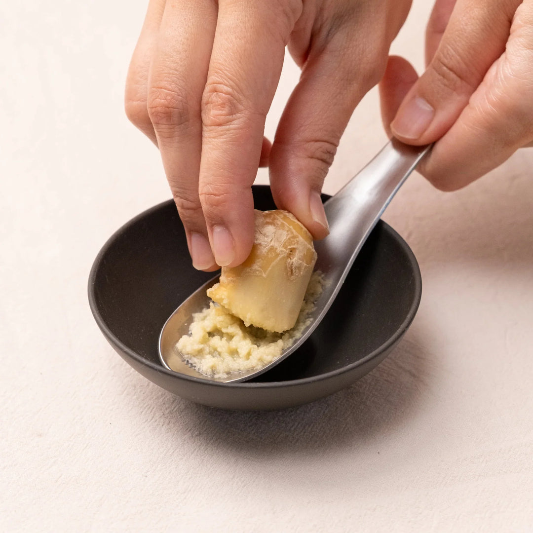 Close up of Grater Spoon grating fresh ginger Japanese stainless steel condiment tool