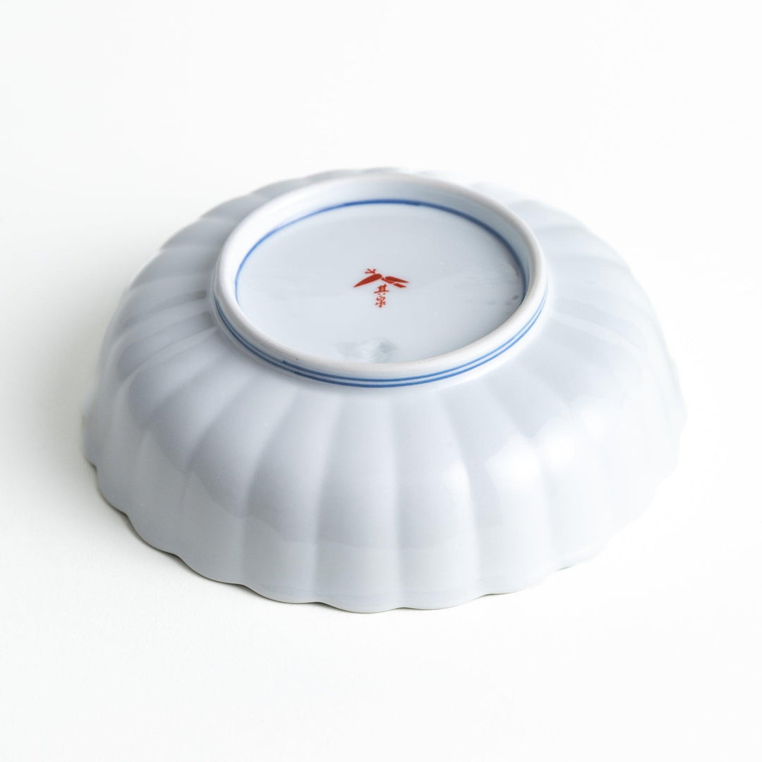 A round, deep cereal bowl with a scalloped edge, featuring a central floral design surrounded by a colorful pattern in blue, red, and green on a white background.