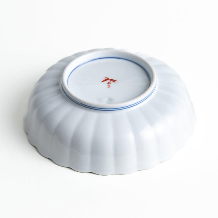 A round, deep cereal bowl with a scalloped edge, featuring a central floral design surrounded by a colorful pattern in blue, red, and green on a white background.
