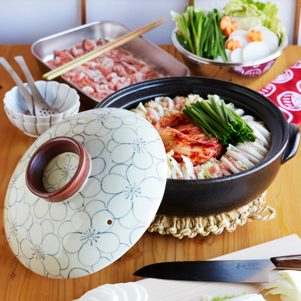 Japanese donabe clay pot with floral lid, filled with kimchi nabe hot pot of pork, napa cabbage, and vegetables for home cooking.