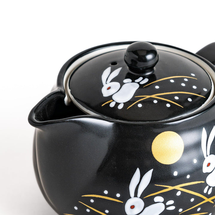 Black teapot featuring white rabbits, golden grasses, and a full moon design, inspired by traditional Japanese autumn motifs.