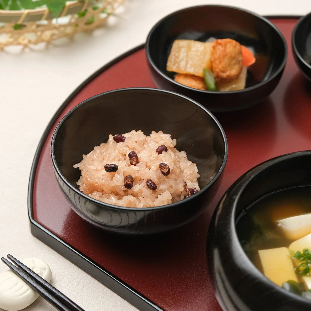 Japanese black lacquered oryoki bowl with sekihan red rice beautifully served on a red traditional tray