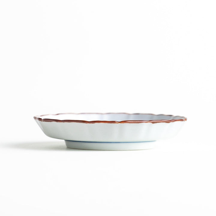 A ceramic dish with a blue and white design, showcasing a pattern of floral motifs and a depiction of Mount Fuji.