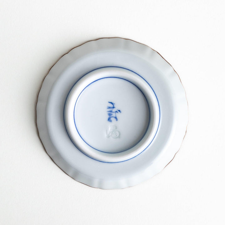 A ceramic dish with a blue and white design, showcasing a pattern of floral motifs and a depiction of Mount Fuji.