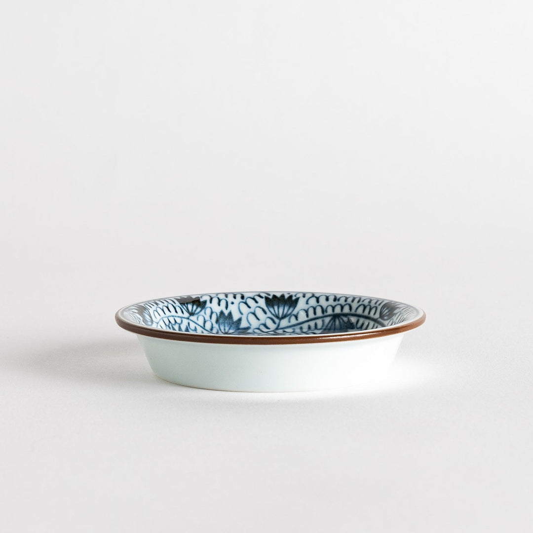 A small saucer adorned with detailed blue leaf patterns on a white background.