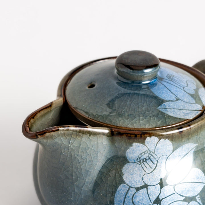 Stylish blue ceramic teapot with a delicate white camellia flower pattern. Perfect for enjoying your favorite tea.