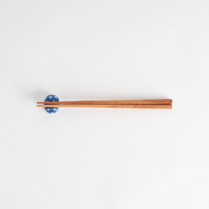 A blue and white rounded ceramic chopstick rest with a starburst pattern.