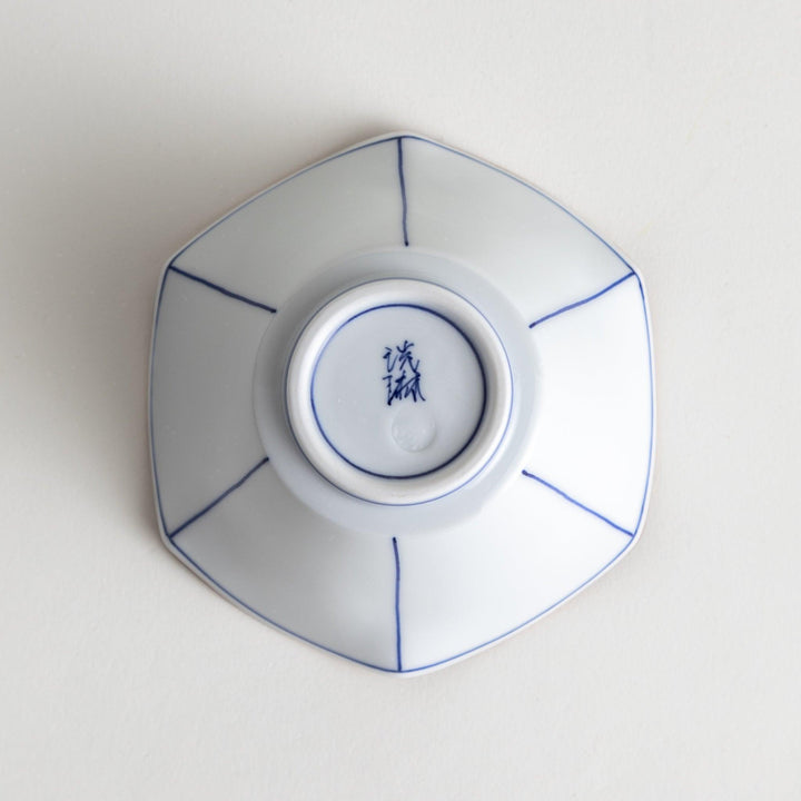 A white ceramic bowl with a flared, scalloped edge and simple blue line detailing.