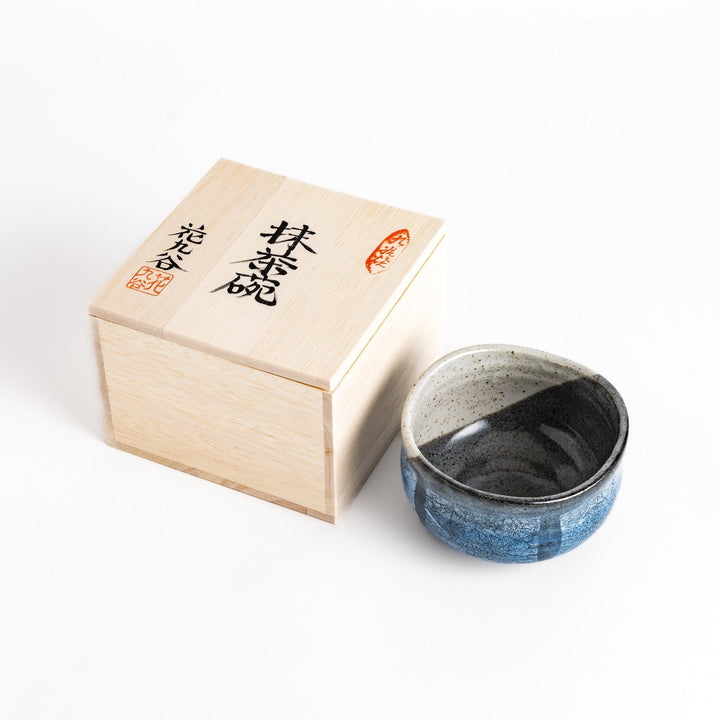 Blue and black matcha bowl with a unique glazed finish, presented in a traditional wooden box, perfect for a special tea ceremony.