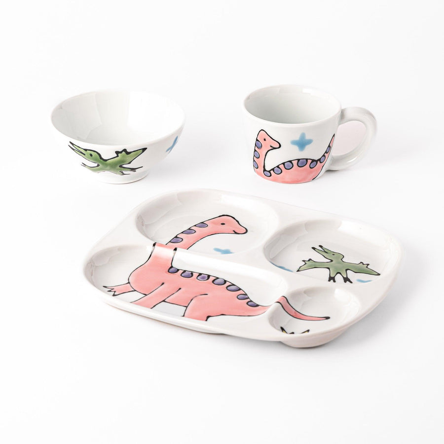 Fun kids' dining set featuring a dinosaur-themed plate, bowl, and cup with playful illustrations of a pink Brachiosaurus and green flying dinosaur, perfect for little ones.