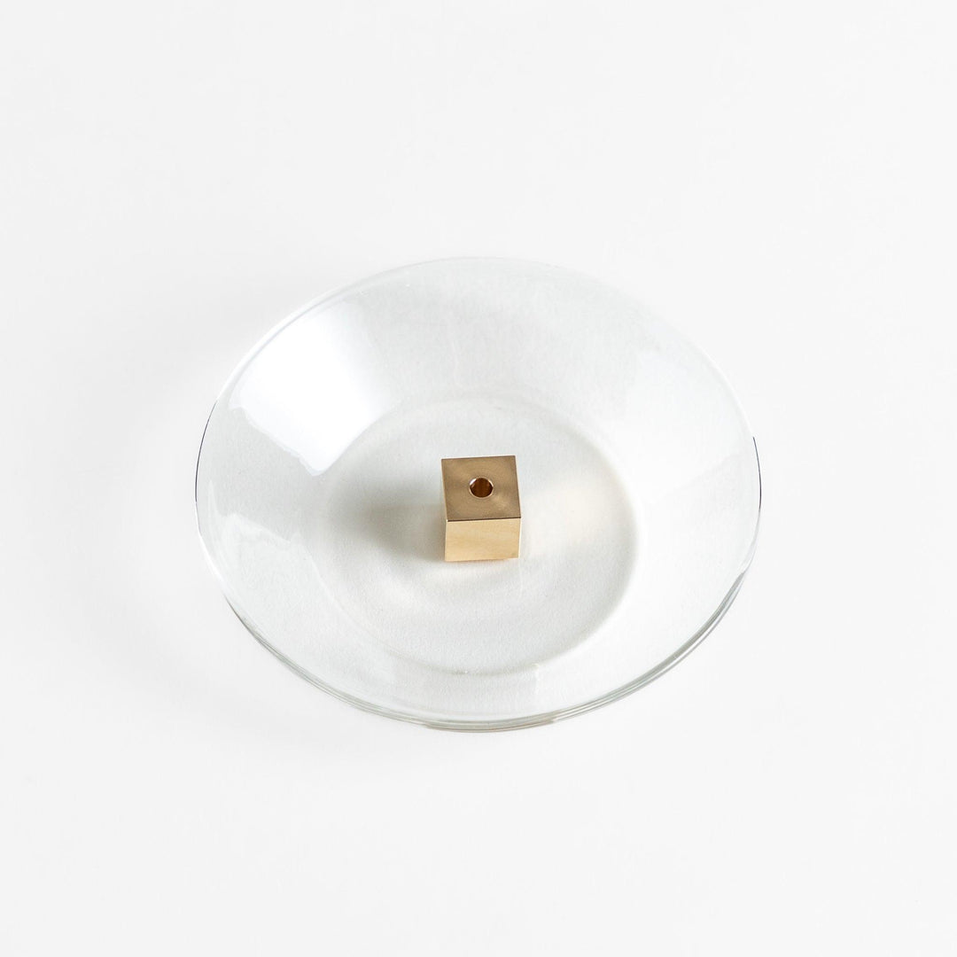 A modern Incense Holder set featuring a transparent glass dish and a brass cube stand, combining minimalist aesthetics with functionality for a refined incense experience.