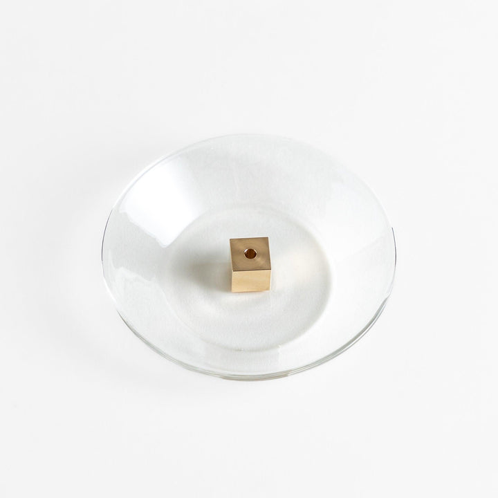A modern Incense Holder set featuring a transparent glass dish and a brass cube stand, combining minimalist aesthetics with functionality for a refined incense experience.