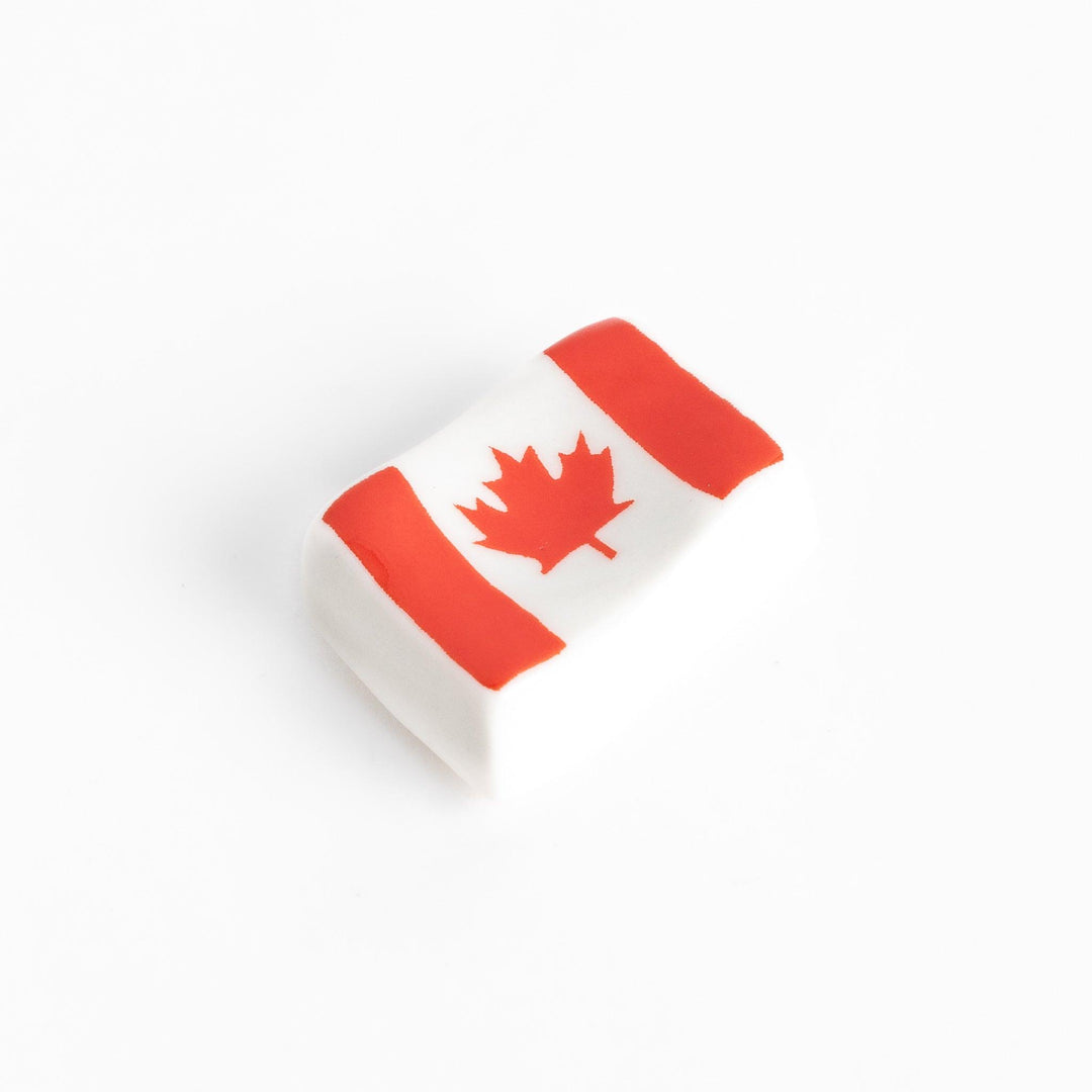 Chopstick rest shaped like the Canadian flag, featuring a red maple leaf in the center, with red borders on each side.