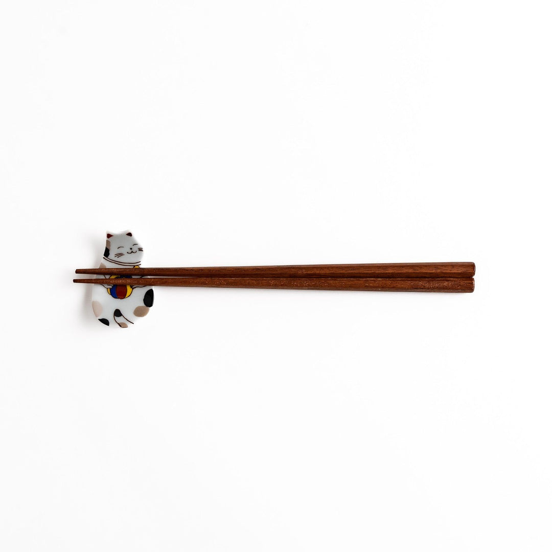 Ceramic cat-shaped chopsticks rest with a ball, shown holding chopsticks, highlighting its detailed and colorful design for elegant dining.