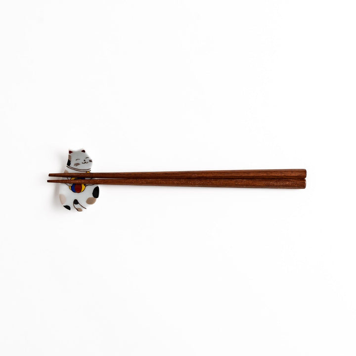 Ceramic cat-shaped chopsticks rest with a ball, shown holding chopsticks, highlighting its detailed and colorful design for elegant dining.