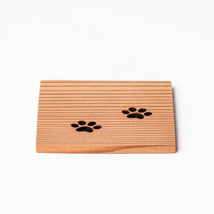 Square cedar mini coaster with two laser-cut cat paw prints, natural warm wood grain, perfect for small cups or glasses.