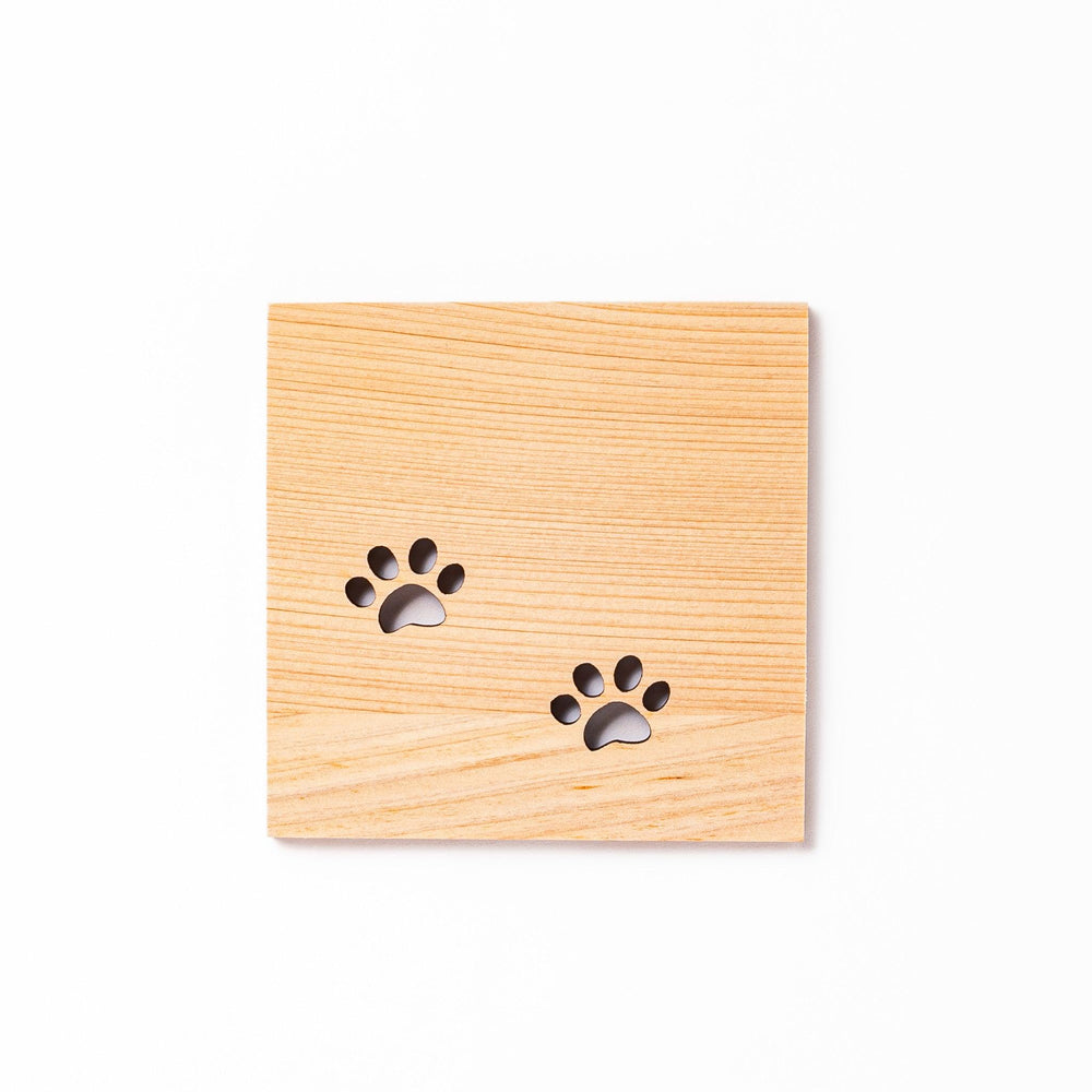Square hinoki wood mini coaster with two cat paw cutouts, showcasing light grain and protecting surfaces.