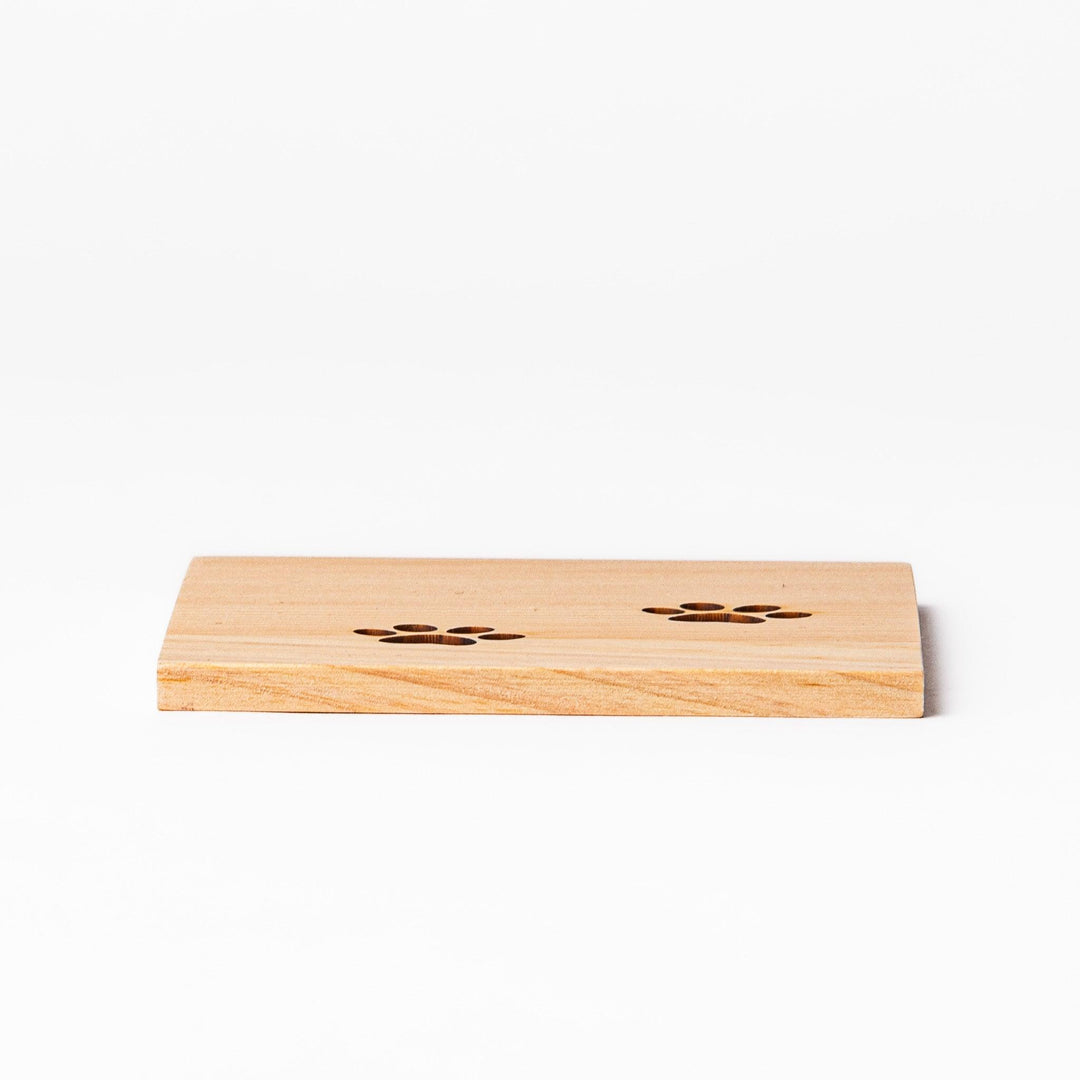 Square hinoki wood mini coaster with two cat paw cutouts, showcasing light grain and protecting surfaces.