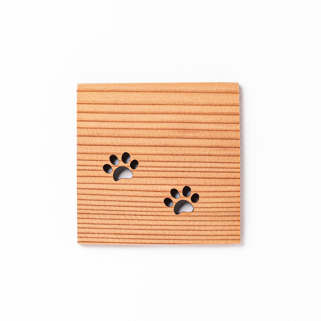 Square cedar mini coaster with two laser-cut cat paw prints, natural warm wood grain, perfect for small cups or glasses.