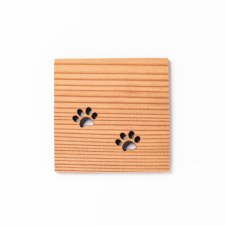 Square cedar mini coaster with two laser-cut cat paw prints, natural warm wood grain, perfect for small cups or glasses.