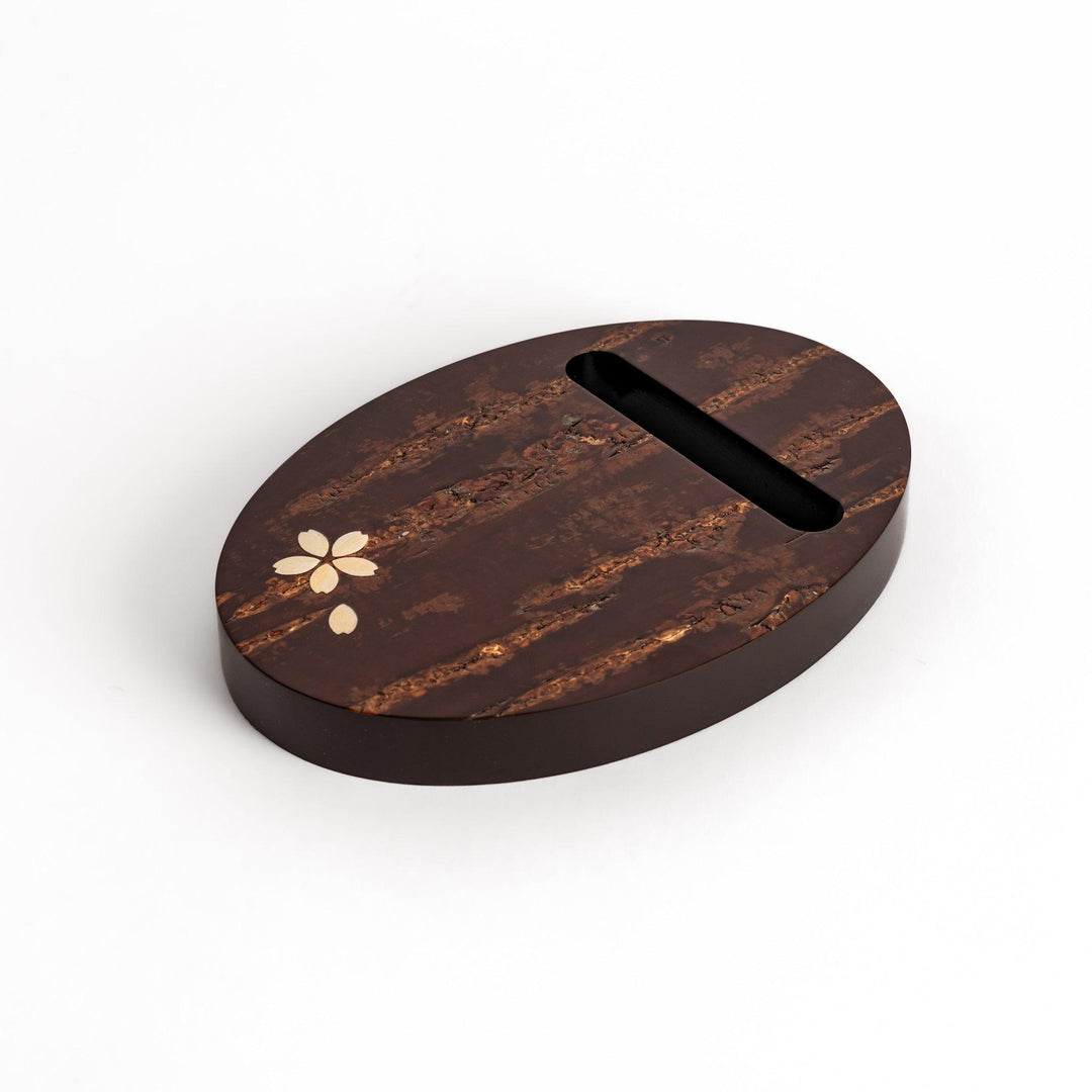 Oval-shaped cherry bark teapot rest with a beautiful natural grain and a delicate cherry blossom inlay, adding a touch of elegance to your tea time.