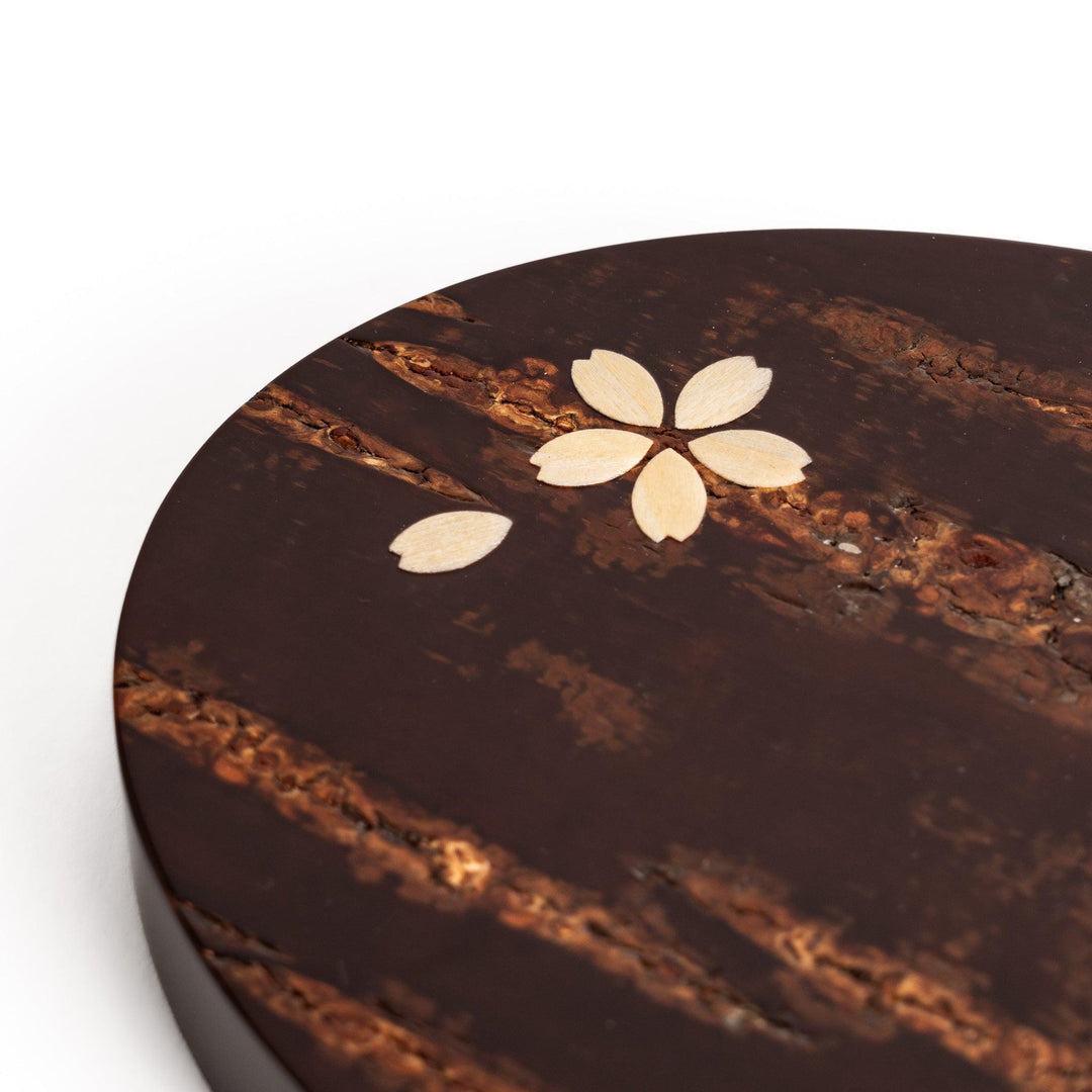 Oval-shaped cherry bark teapot rest with a beautiful natural grain and a delicate cherry blossom inlay, adding a touch of elegance to your tea time.