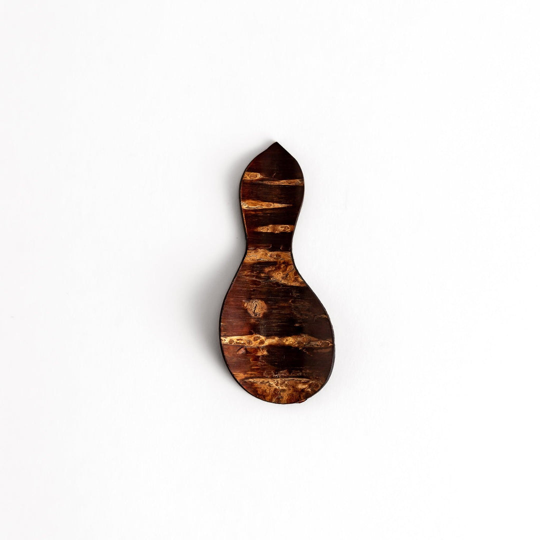 Elegant cherry bark tea scoop with a unique curved design and beautiful wood grain, perfect for measuring loose leaf tea with a touch of natural artistry