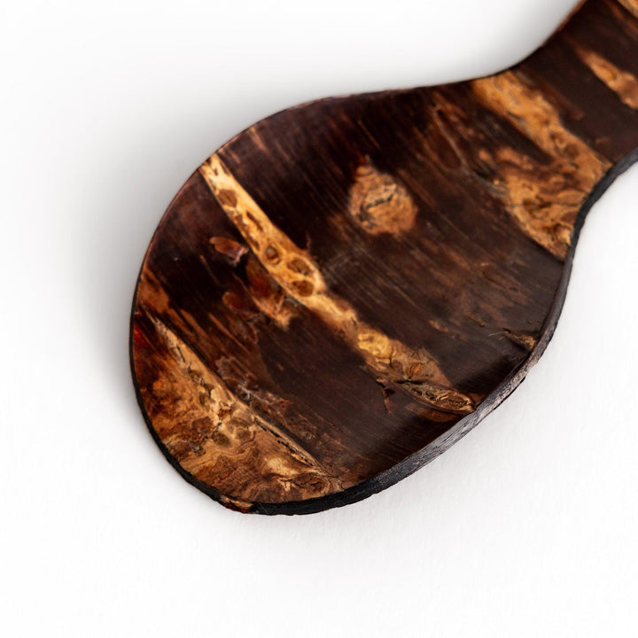 Elegant cherry bark tea scoop with a unique curved design and beautiful wood grain, perfect for measuring loose leaf tea with a touch of natural artistry