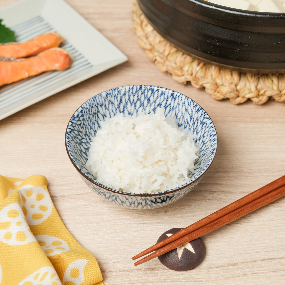 Steaming white rice served in a blue patterned Japanese bowl, paired with wooden chopsticks for an authentic dining experience.