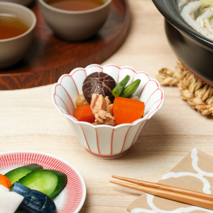 White scalloped Japanese bowl with red vertical lines, filled with simmered vegetables including carrot, shiitake mushroom, green beans, and chicken for a traditional side dish.