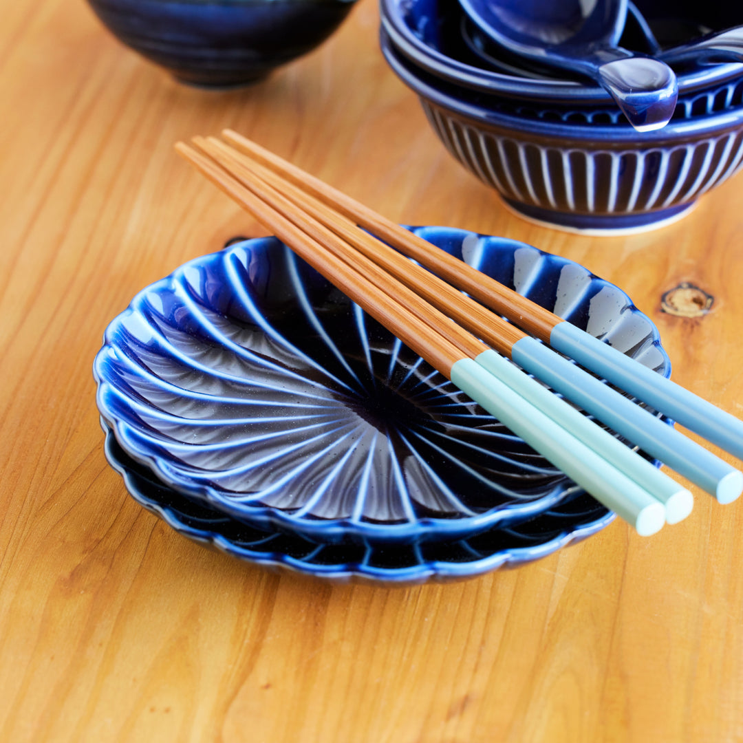 Japanese indigo blue ceramic plates with spiral design, paired with wooden chopsticks featuring light blue handles.