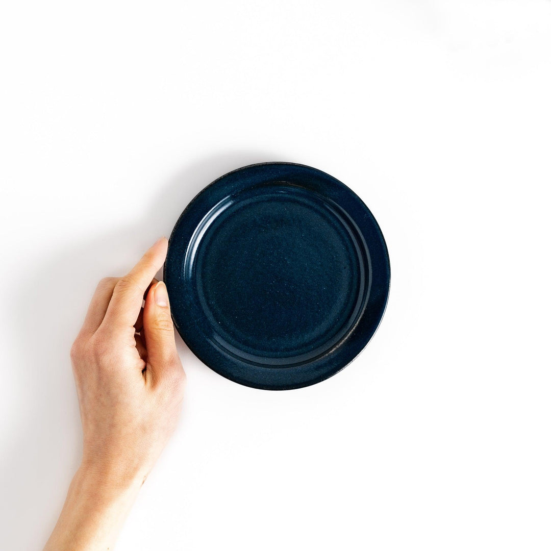 Hand-held blue ceramic dessert plate showcasing its sleek glossy surface and compact size, ideal for everyday dining or special occasions.
