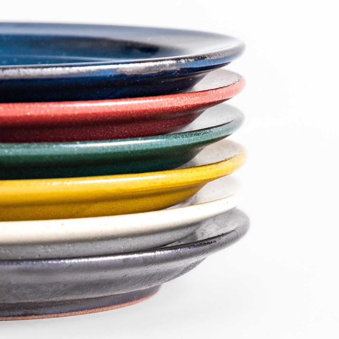 A stack of six colorful dessert plates in blue, red, green, yellow, white, and black, each with a smooth, glossy finish, perfect for adding a pop of color to your table.







