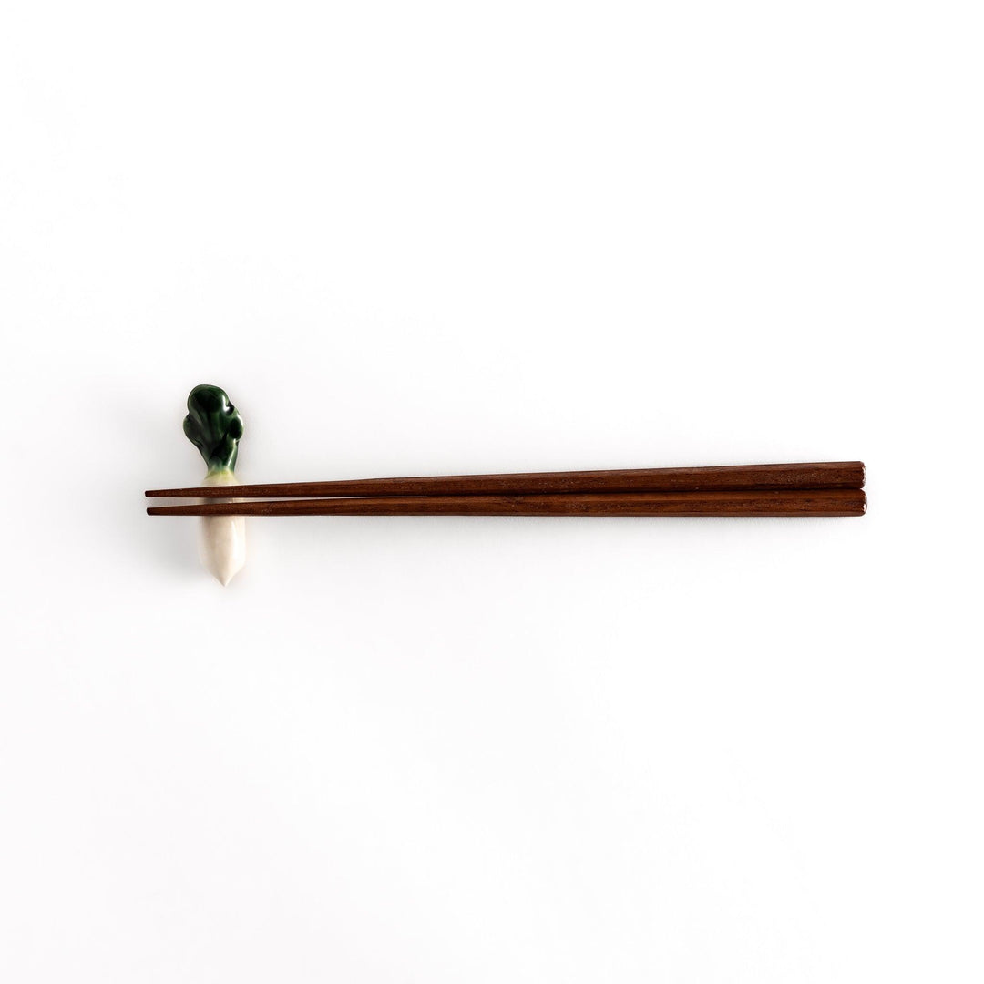 Wooden chopsticks resting on the daikon radish-shaped ceramic chopstick rest, highlighting its elegant and functional design.