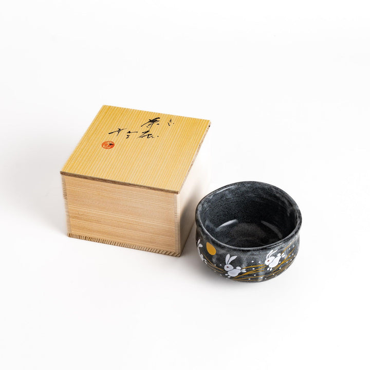 Black matcha bowl with a playful rabbit and moon design, presented in a traditional wooden box, ideal for a unique tea ceremony experience.