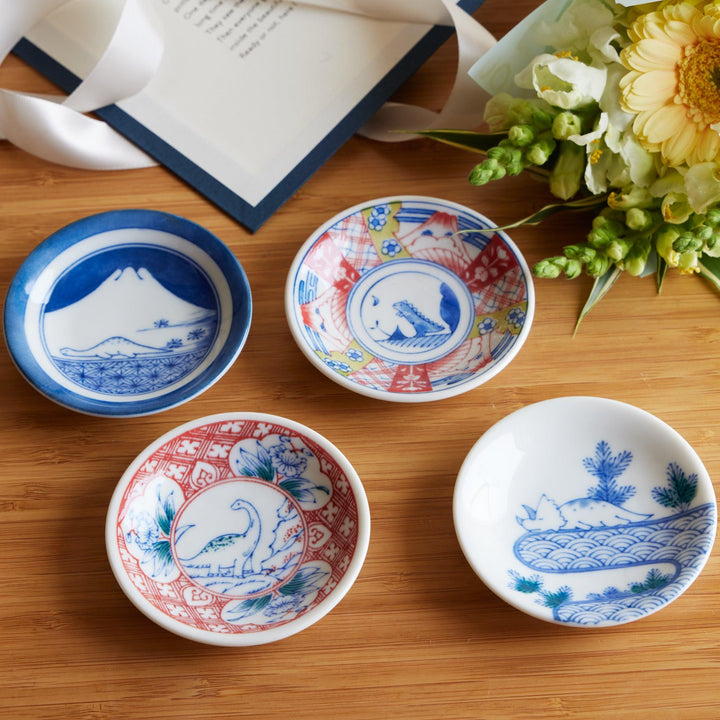 A set of four beautiful sauce dishes featuring traditional Japanese designs, including Mount Fuji, a dinosaur, and playful animal motifs, complemented by floral accents.








