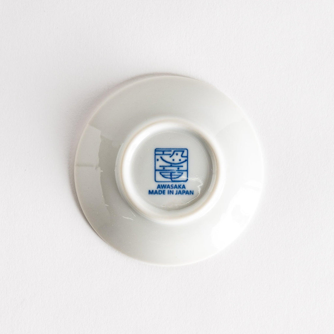 A set of four small, decorative porcelain plates in a gift box, each plate featuring a different dinosaur design in blue and red.