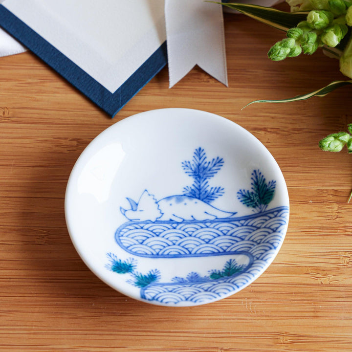A set of four small, decorative porcelain plates in a gift box, each plate featuring a different dinosaur design in blue and red.