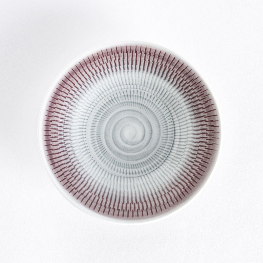 A light purple dessert plate with radiating spiral-striped patterns, viewed from the front.