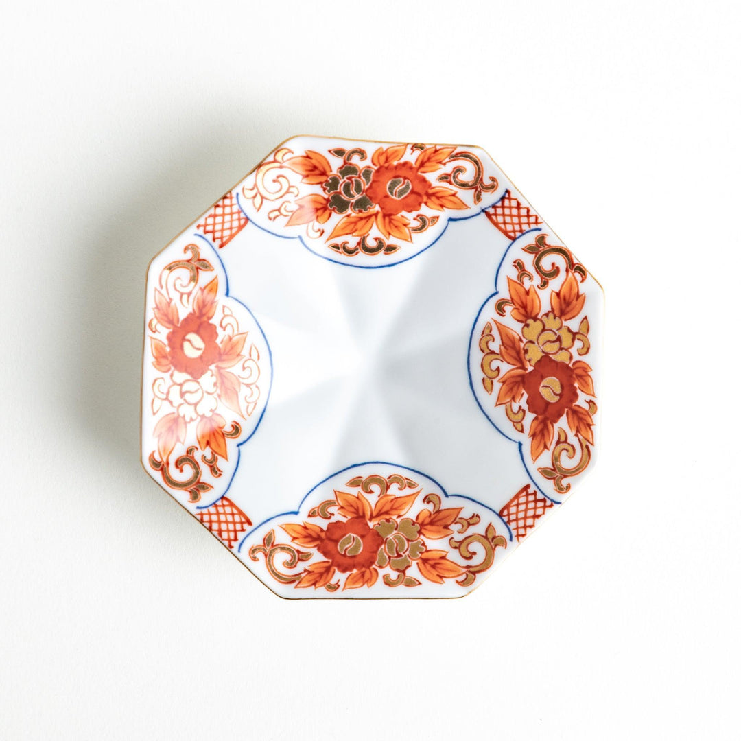Octagonal plate with ornate orange floral patterns on a white background.
