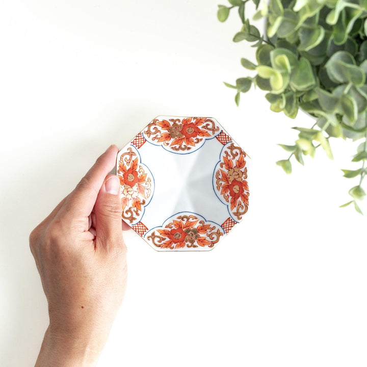 Octagonal plate with ornate orange floral patterns on a white background.
