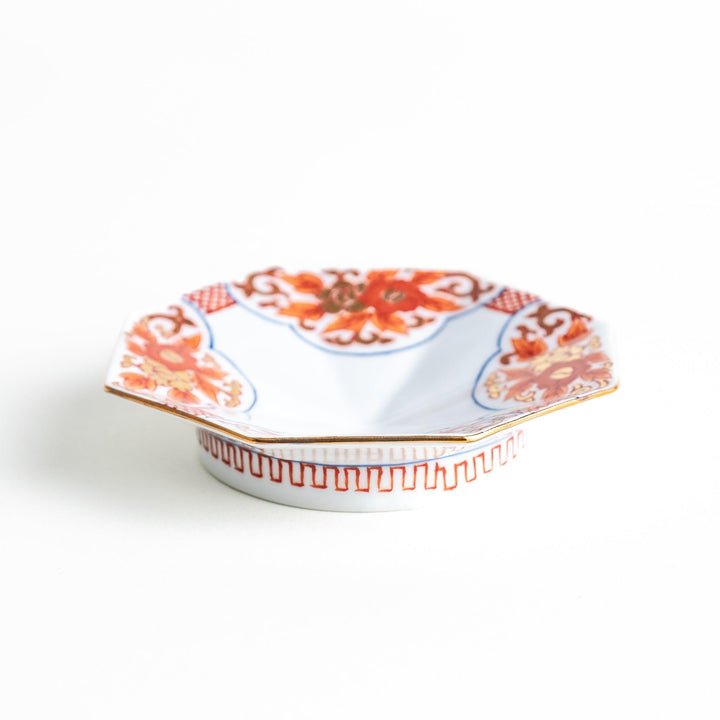 Octagonal plate with ornate orange floral patterns on a white background.
