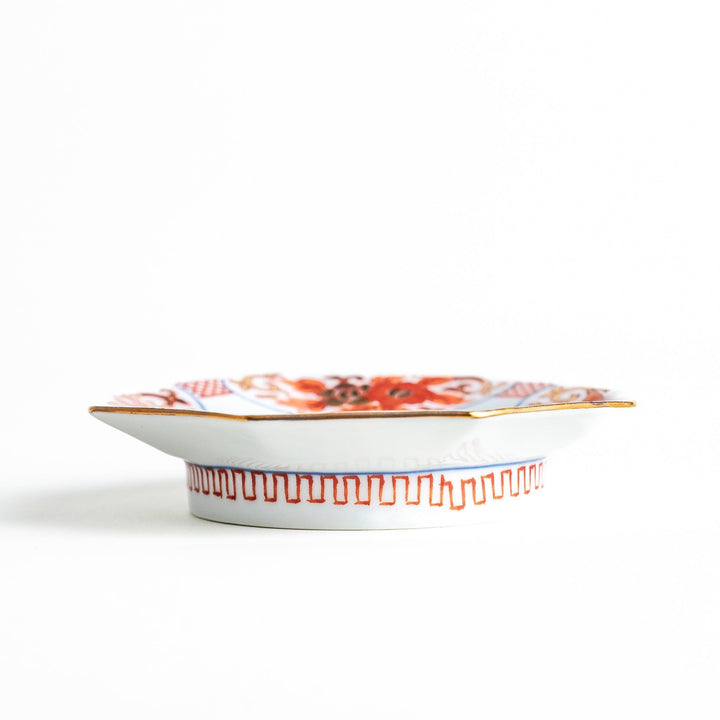Octagonal plate with ornate orange floral patterns on a white background.
