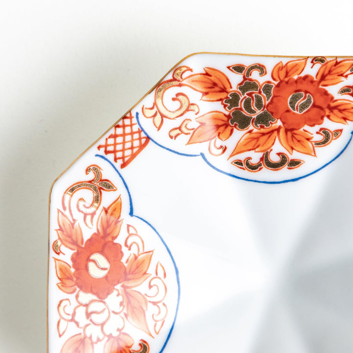 Octagonal plate with ornate orange floral patterns on a white background.
