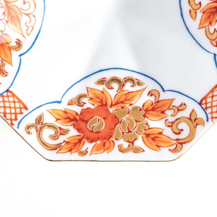 Octagonal plate with ornate orange floral patterns on a white background.
