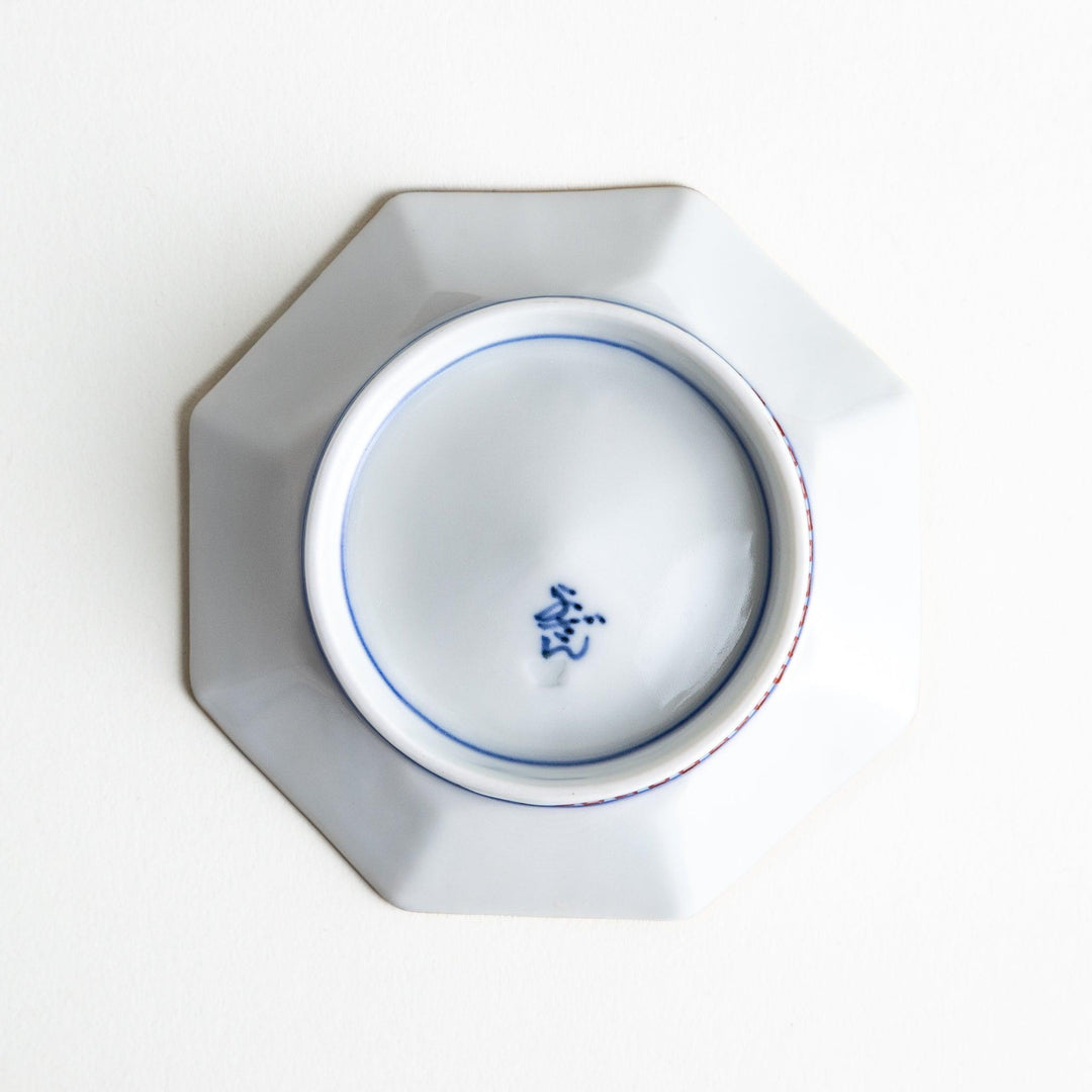 Octagonal plate with ornate orange floral patterns on a white background.
