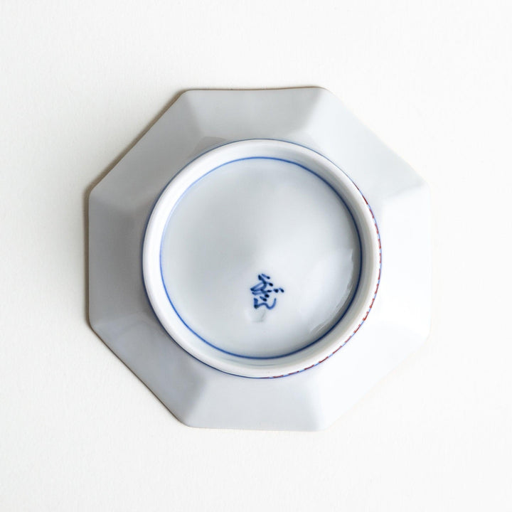 Octagonal plate with ornate orange floral patterns on a white background.
